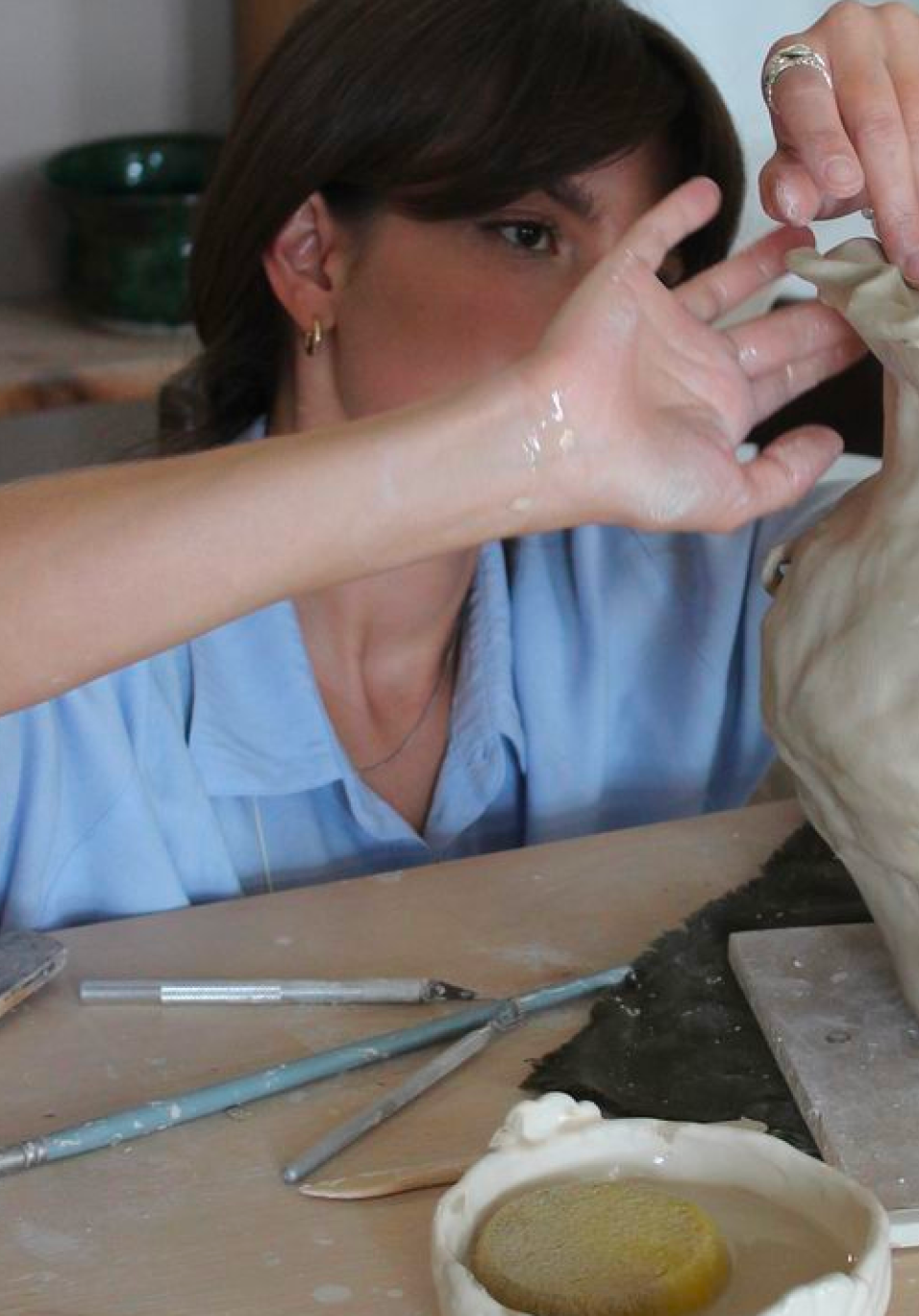 Hands shaping clay on a pottery wheel